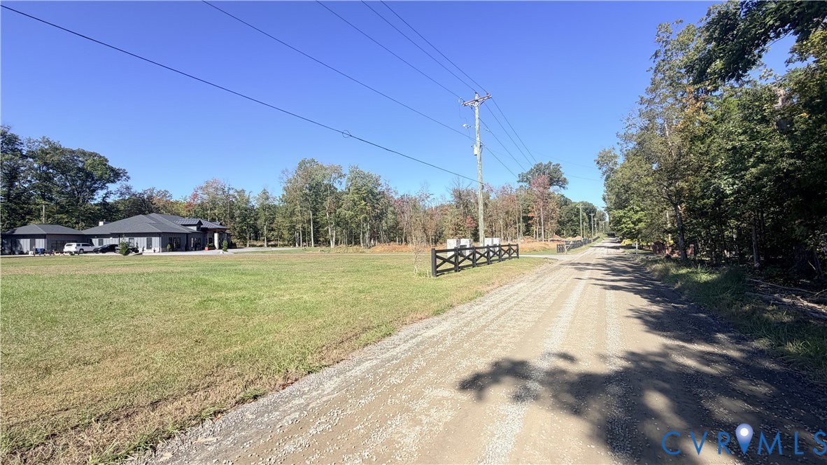 Expansive acreage featuring cleared level terrain, mature tree borders, and a dark-finish post-and-rail fence