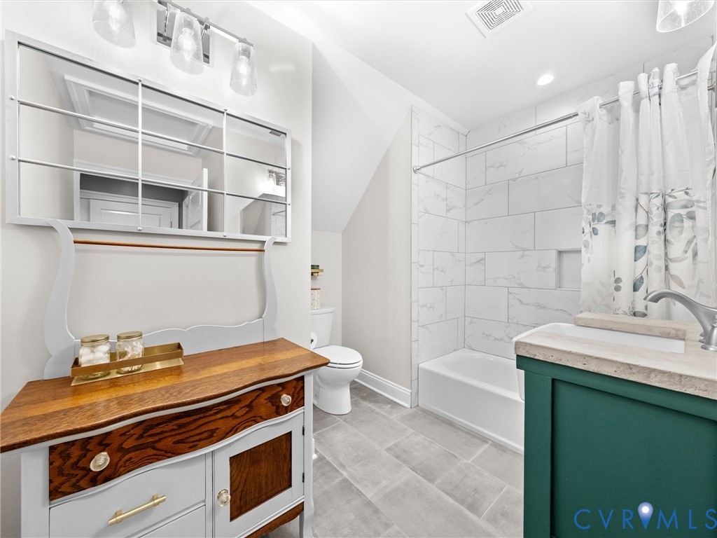 The spacious upper-level hall bath features a custom-made single-sink vanity, tile flooring, and a tub/shower combination with a tile surround.
