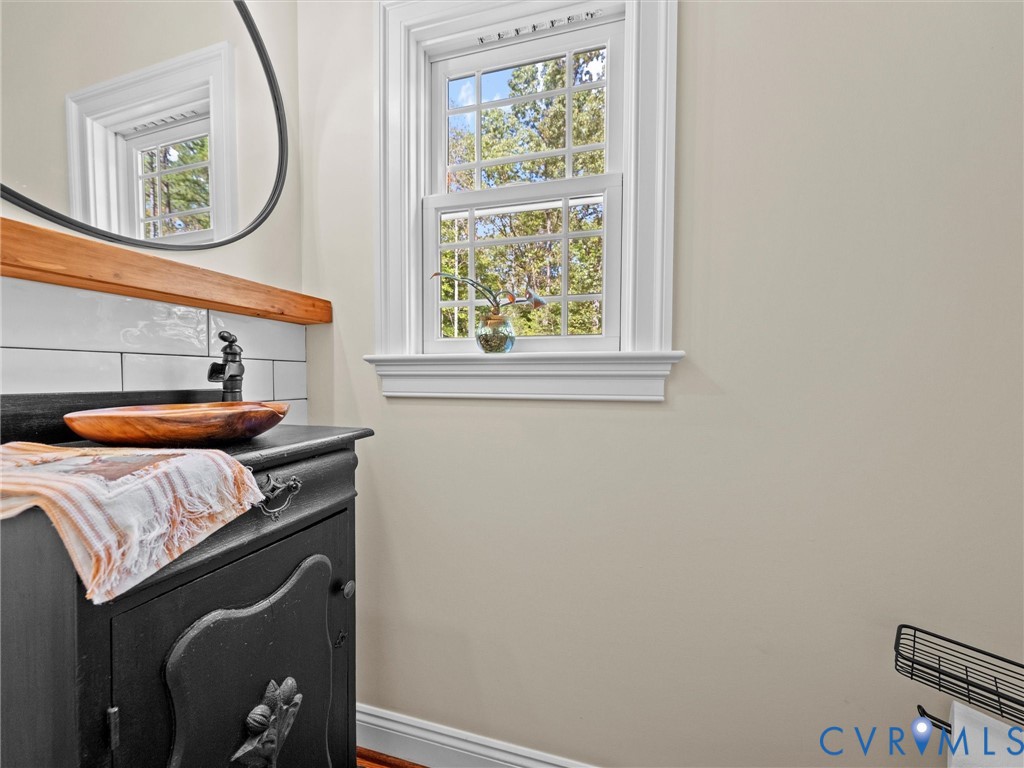 The charming first-floor half bath features a custom-built vanity, stylish fixtures, and natural light, adding a touch of character and convenience for guests.