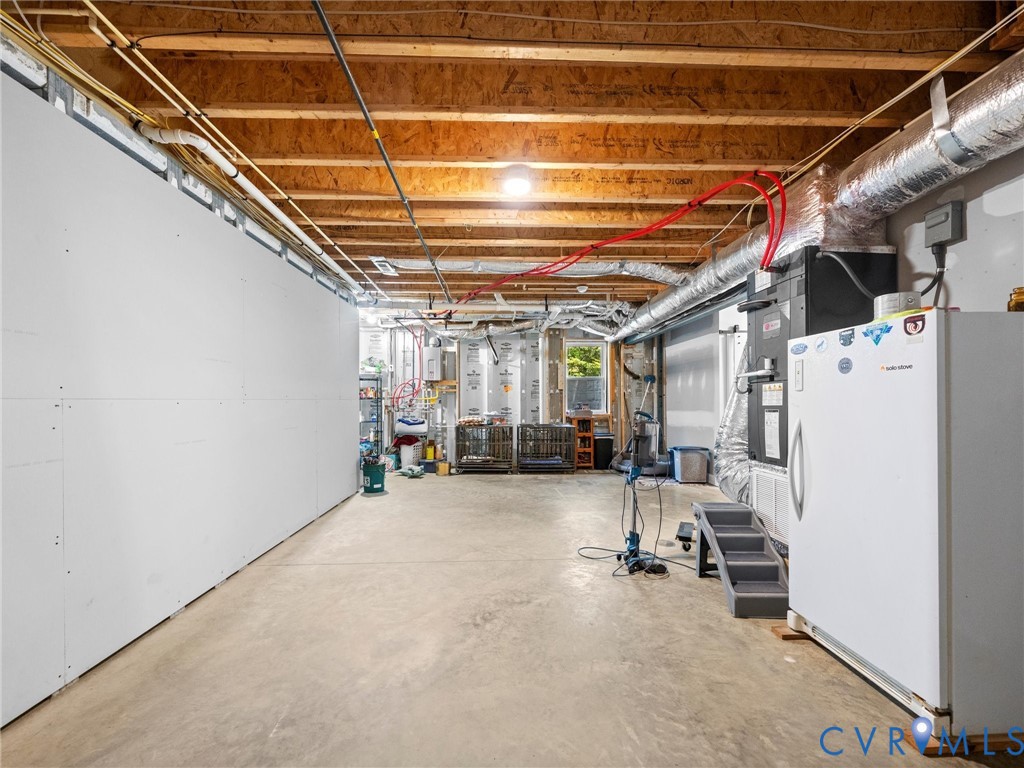Another view of the spacious, heated and cooled walk-out basement highlights the generous open layout, exposed ceiling beams, and ample room for storage, hobbies, recreation, or future finishing possibilities!