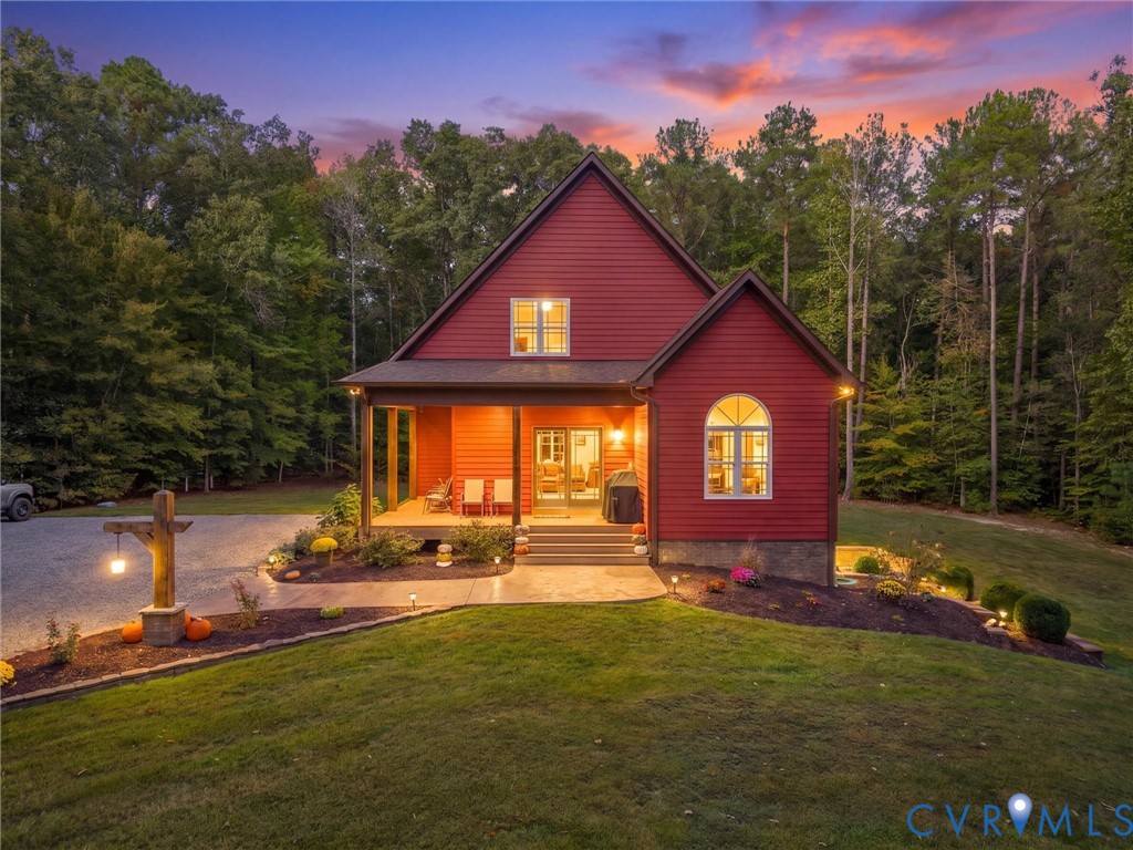 A picture-perfect evening at this charming country retreat! The warm glow of the home's exterior lighting, beautifully landscaped grounds, and breathtaking sunset create an inviting atmosphere. A peaceful place to unwind and enjoy the beauty of country living!