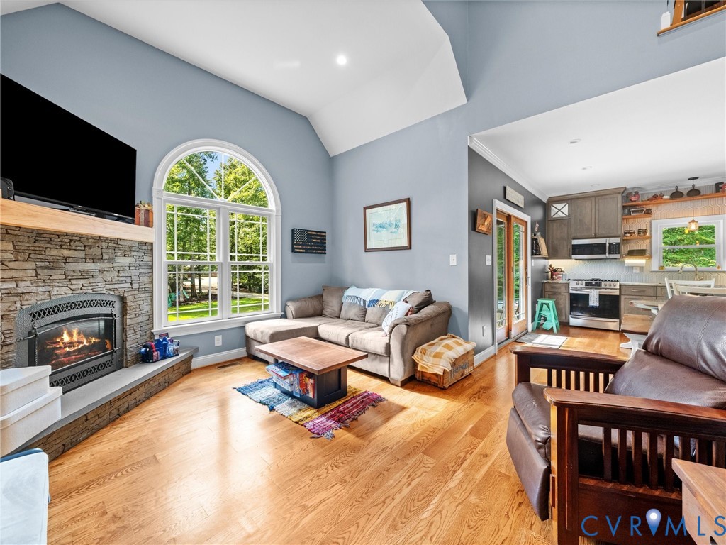 The stunning two-story family room features soaring ceilings, a beautiful stacked stone gas fireplace, an elegant arched window, and gleaming hardwood floors. Open to the custom kitchen, this inviting space is perfect for relaxing or entertaining!