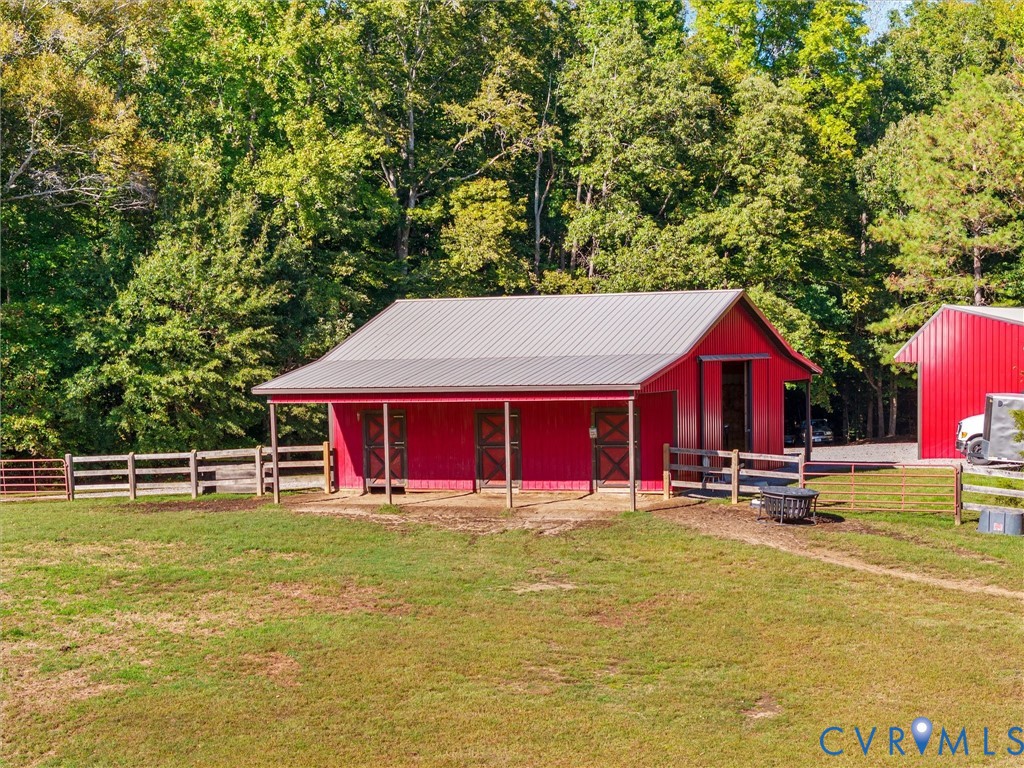The charming 3-stall horse barn features a tack room, hay and storage area, and spacious 8-foot covered porches. Surrounded by beautiful fenced pastures and mature trees, this thoughtfully designed barn offers convenience, functionality, and a picturesque setting for your horses!