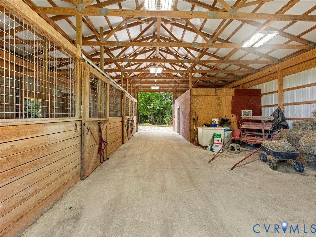 The charming 3-stall horse barn features a spacious center aisle, exposed wood trusses, attractive wood stall fronts, and a generous hay storage area with potential for conversion into two additional stalls. Convenient access to fenced pastures makes everyday horse care a breeze!