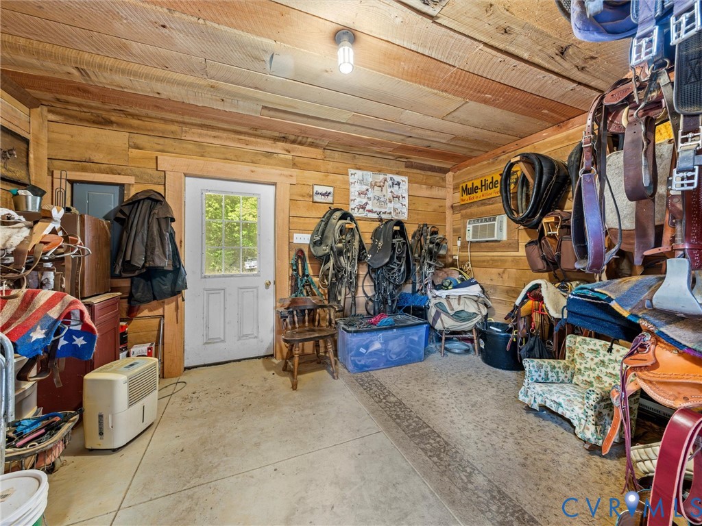 The spacious tack room features rustic wood walls and ceilings, ample room for saddles, bridles, and riding equipment, and convenient exterior access. A practical and inviting space for all your equestrian essentials!