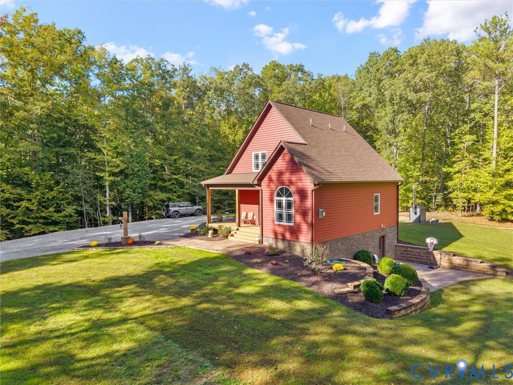 Beautiful tiered landscaping with stacked stone retaining walls, manicured planting beds, and lush green lawns enhances the home's charming exterior. Surrounded by mature trees, this picturesque setting offers a wonderful blend of natural beauty and thoughtful landscaping!