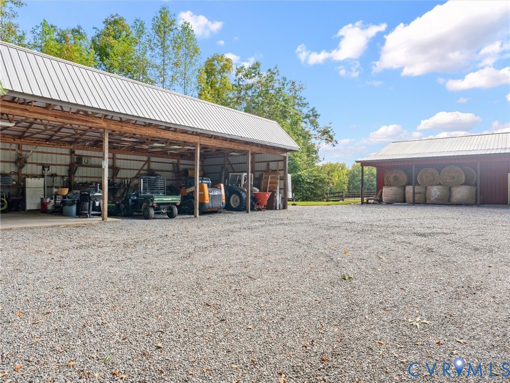 The spacious 4-bay equipment barn features electricity, with one bay offering a concrete floor. Perfect for storing tractors, farm equipment, trailers, and other essentials, with a generous gravel area providing convenient access and maneuverability!