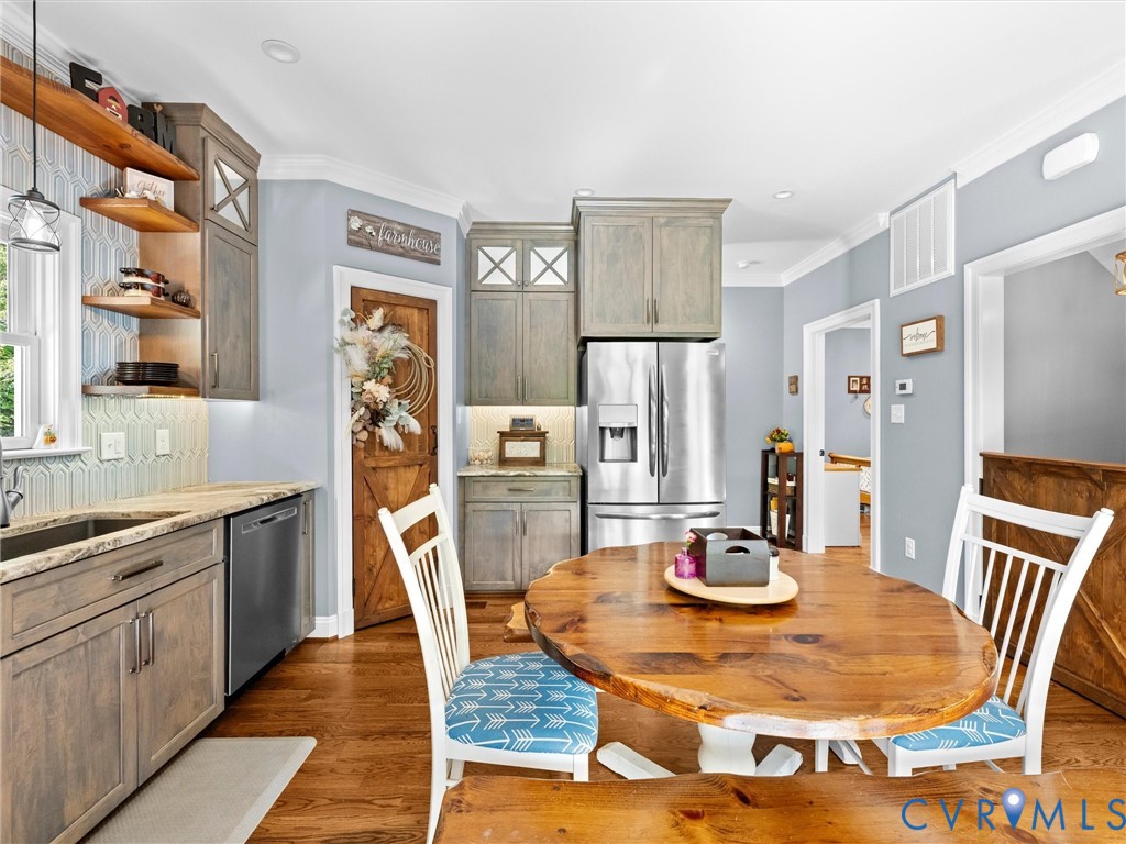 Another view of the beautiful custom kitchen showcases the granite countertops, stainless steel appliances, abundant cabinetry, and hardwood floors. A charming wood door leads to the spacious walk-in pantry featuring wood shelving for convenient storage and organization!