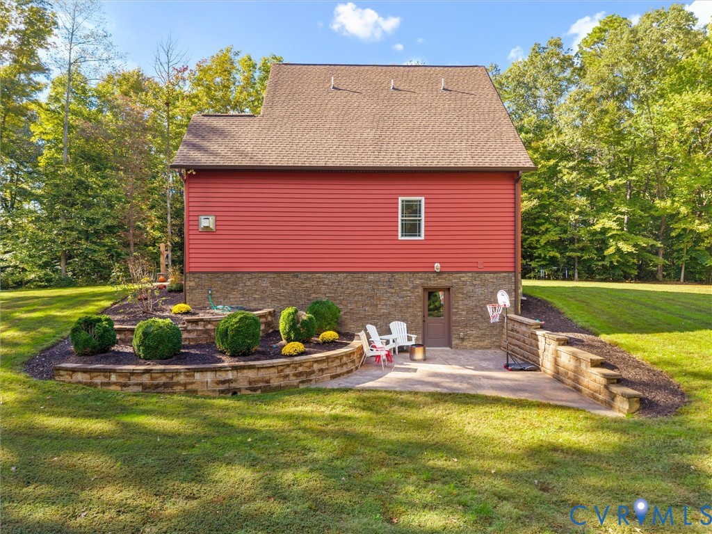 Beautifully designed outdoor living space featuring a stamped concrete patio with direct access from the walk-out basement, stunning tiered stacked stone retaining walls, and thoughtfully landscaped planting beds. A perfect setting for relaxing or entertaining while enjoying the peaceful surroundings!
