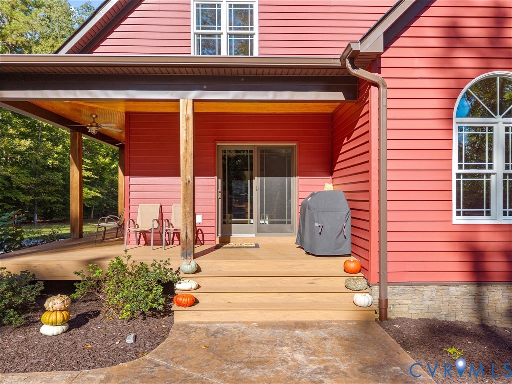 The inviting covered porch features low-maintenance composite decking, beautiful white oak posts, and sliding glass doors providing convenient access to the kitchen. A wonderful spot to relax, entertain, and enjoy the peaceful country setting!