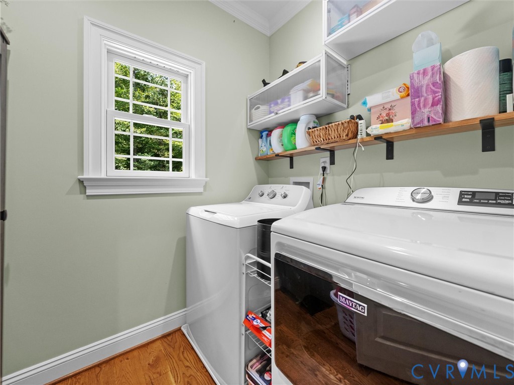 Convenient first-level laundry room featuring built-in cabinetry, countertop space for folding, and a window providing natural light. Thoughtfully designed for everyday functionality and organization!