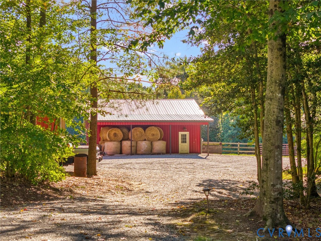 A picturesque approach through mature trees reveals the charming red horse barn, surrounded by beautiful fenced pastures and peaceful woodlands. A welcoming glimpse of the equestrian lifestyle and natural beauty this property has to offer!