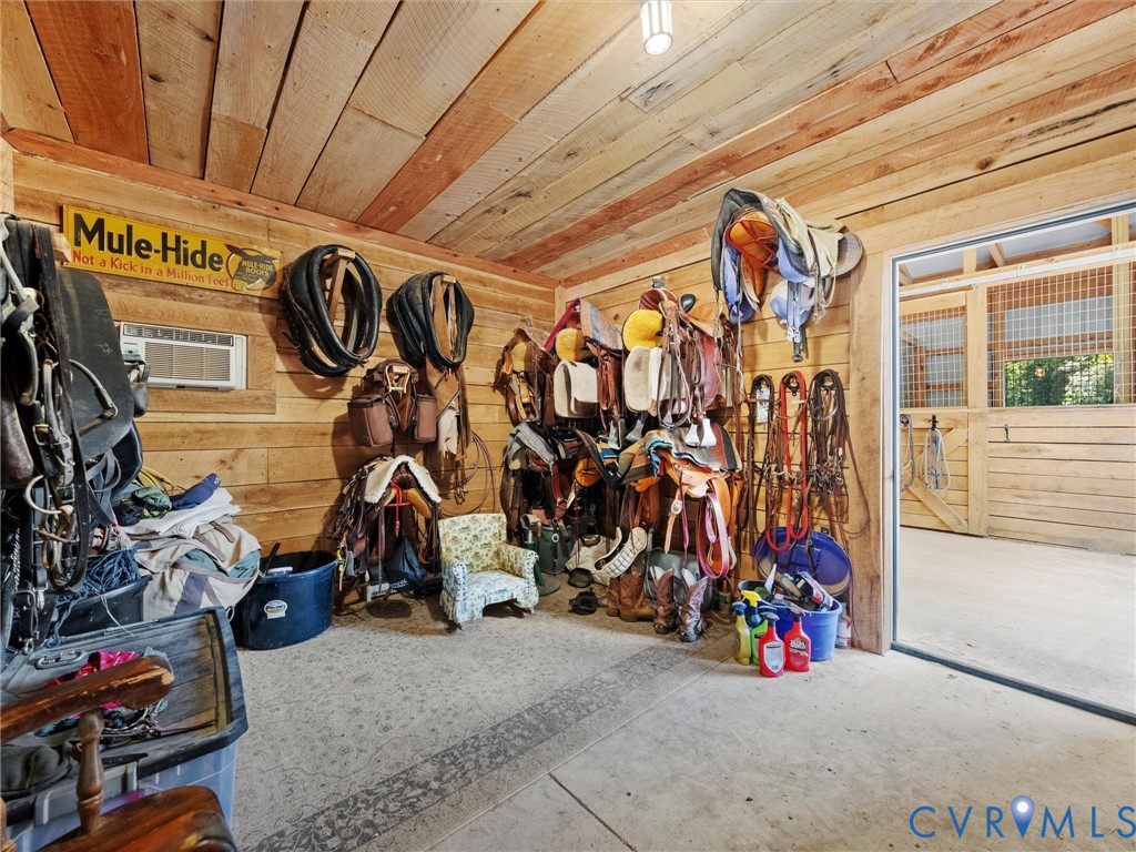 The spacious tack room features rustic wood walls and ceilings, ample storage for saddles, bridles, and riding equipment, and direct access to the center barn aisle for convenient tacking up and everyday horse care!