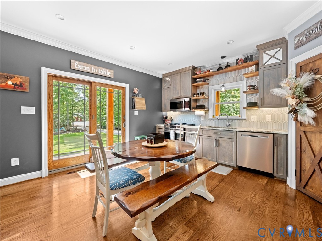 The beautiful custom kitchen features granite countertops, stainless steel appliances, a tile backsplash, and a spacious corner pantry with wood shelving. Gorgeous hardwood floors, generous cabinetry, and a welcoming dining area create the perfect space for everyday living and entertaining!