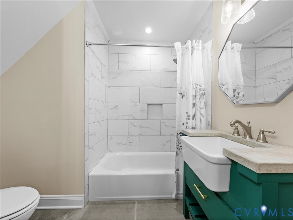 Another view of the spacious upper-level hall bath highlights the custom-made single-sink vanity, tile flooring, tub/shower combination with tile surround.