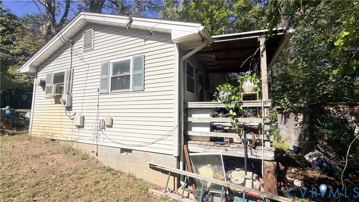 Exterior featuring light-colored horizontal siding, a covered side porch with wood-frame railings, and a concrete block foundation