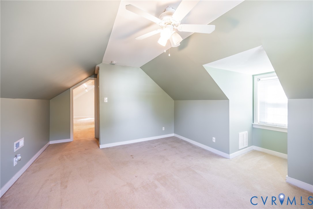 Vaulted ceiling featuring a central multi-blade ceiling fan with integrated lighting and a windowed alcove