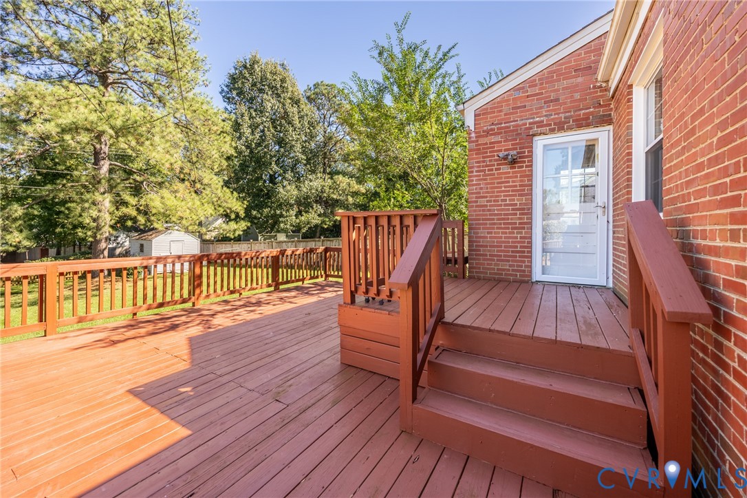 Multi-level wood deck featuring stained railing, brick exterior, and full-glass storm door