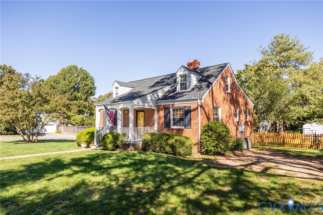 Classic brick exterior featuring a covered front porch, dual dormer windows, asphalt shingle roofing, and decorative shutters Classic brick exterior featuring a covered front porch, dual dormer windows, asphalt shingle roofing, and decorative shutters