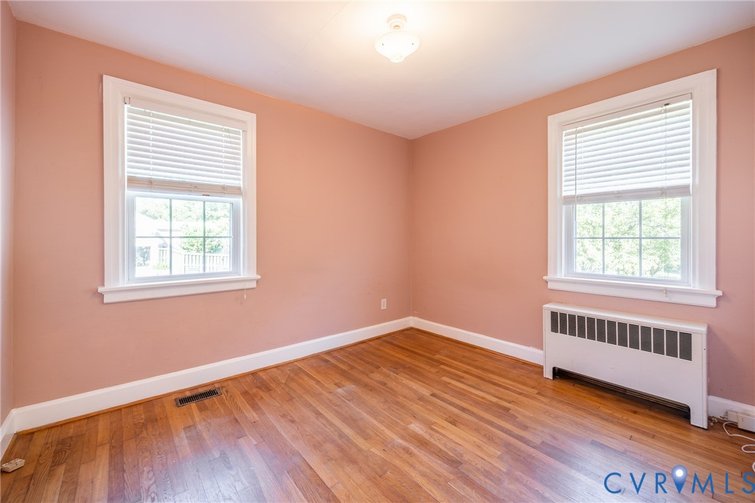 Hardwood flooring, dual windows with blinds, and ceiling-mounted light fixture