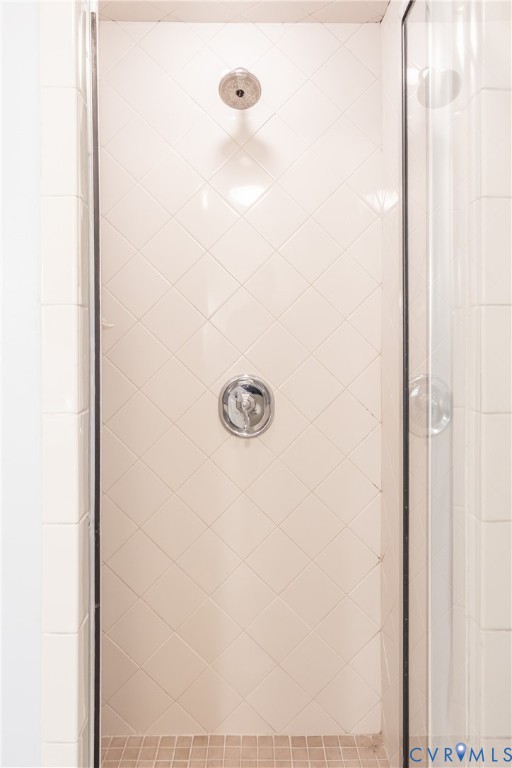 Walk-in shower featuring diamond-patterned wall tile, grid-patterned floor tile, chrome-finish shower head, and chrome-finish pressure balance valve