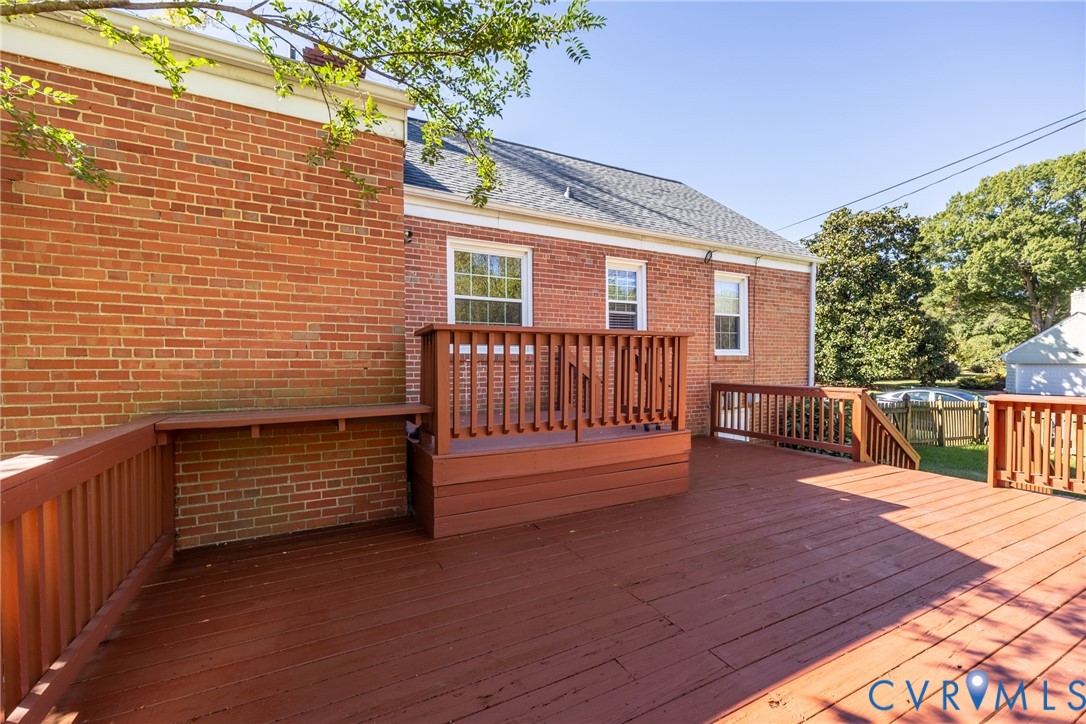 Exterior red brick siding, multi-level wood deck, built-in wooden perimeter bench, and wood railings