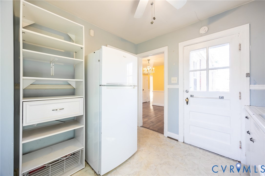 Built-in open shelving unit, white refrigerator, and exterior door with multi-pane glass insert