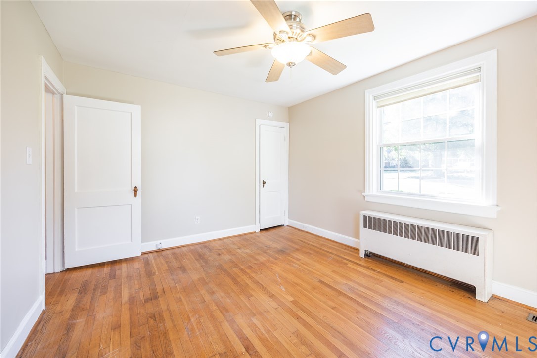 Hardwood flooring, multi-pane window with trim, central ceiling fan with integrated lighting, and two-panel interior doors
