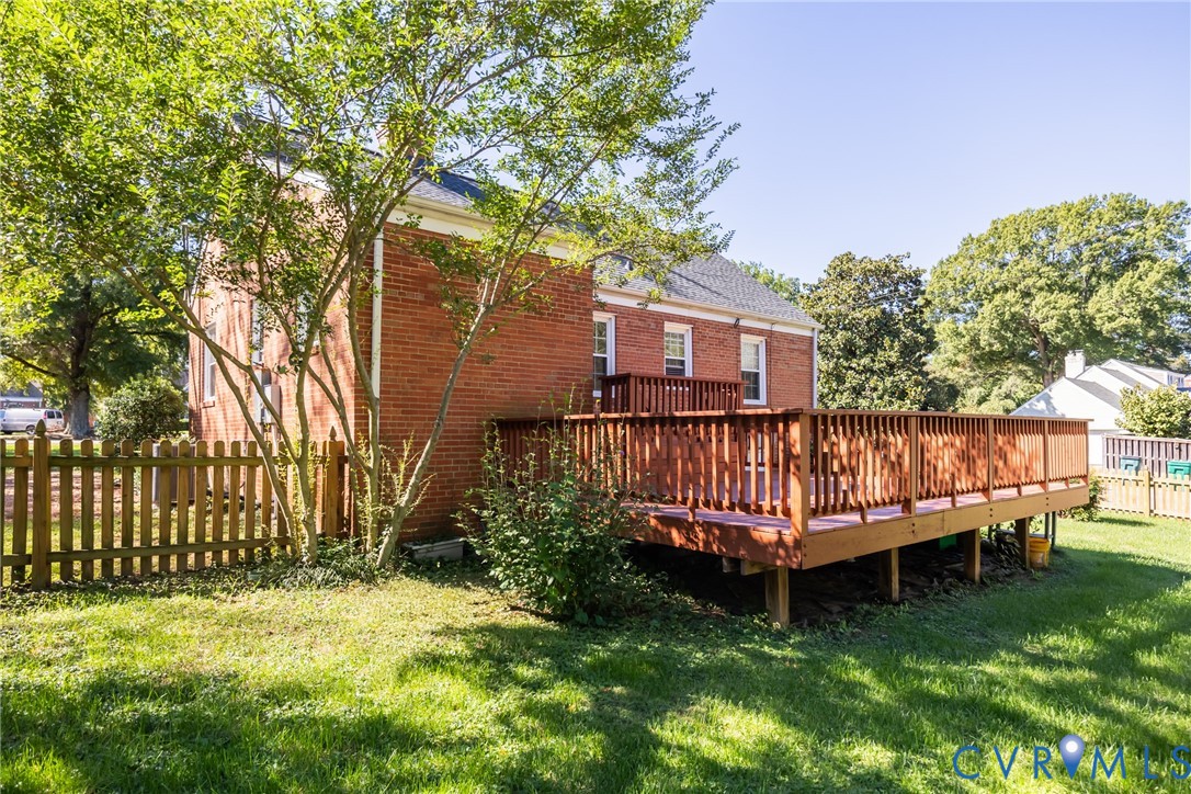 Brick exterior featuring a spacious raised wooden deck and a surrounding wood-slat privacy fence