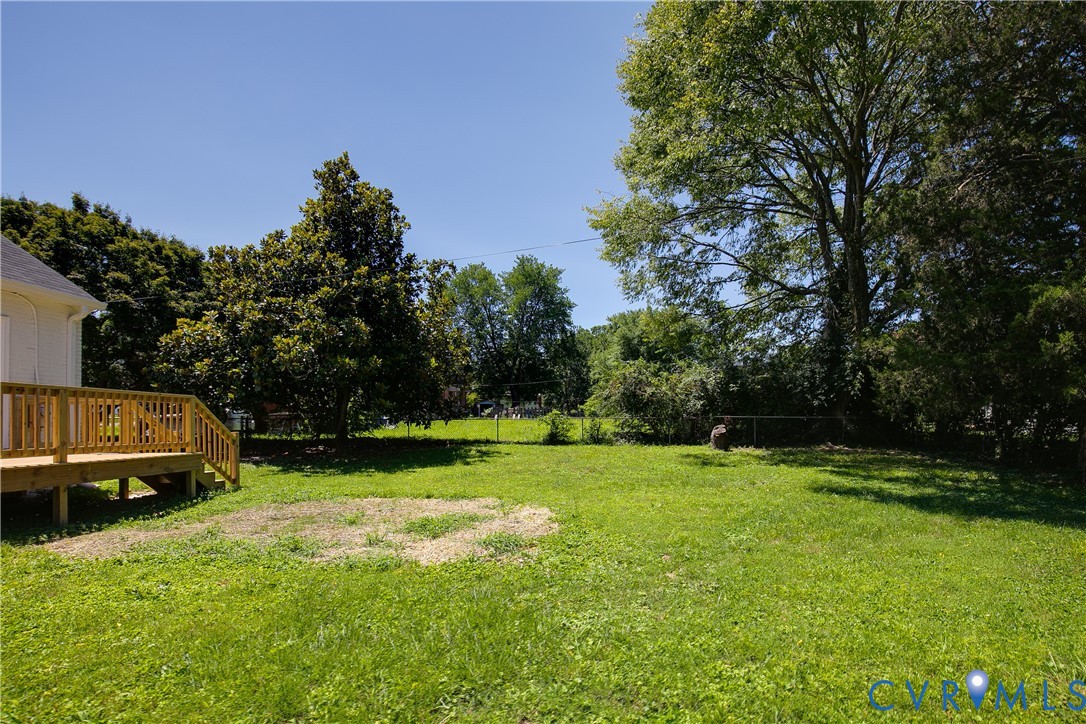 Expansive grassy yard featuring a newly constructed wood deck with railings and steps