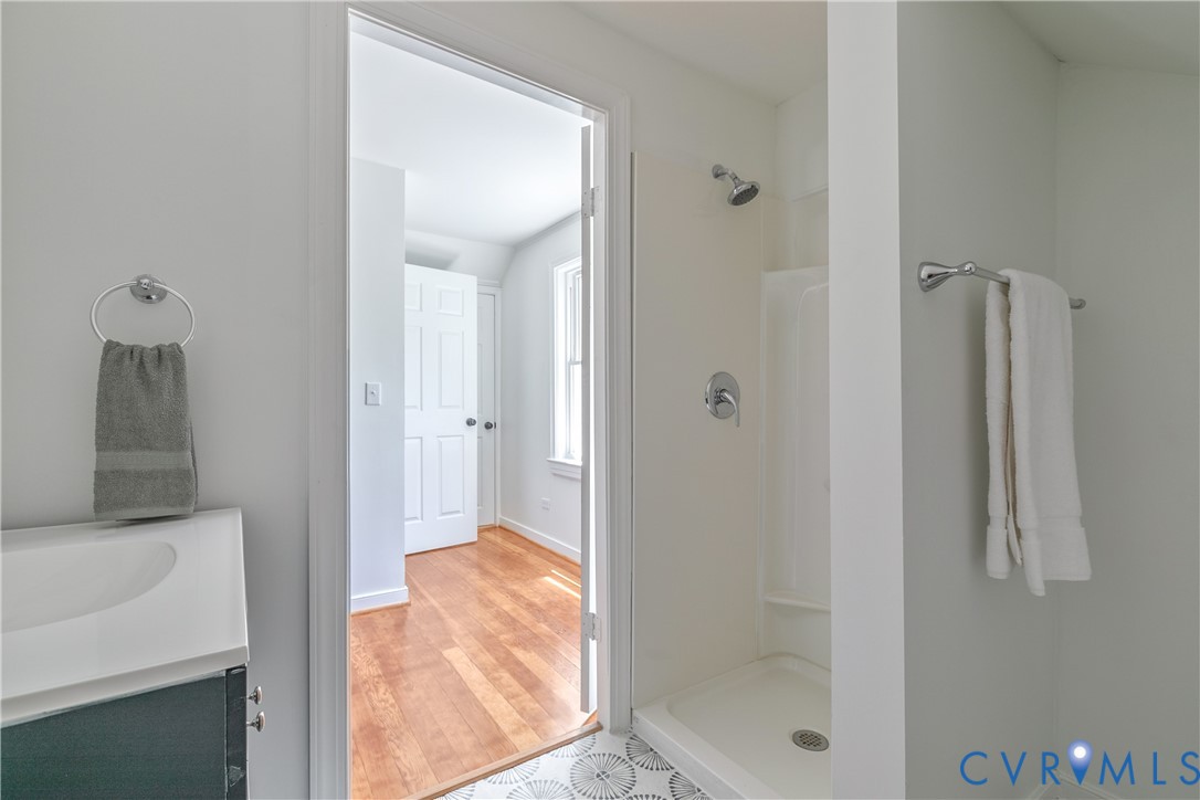 Compact bathroom featuring a shower with chrome fixtures, a patterned floor tile, and a vanity with a white countertop