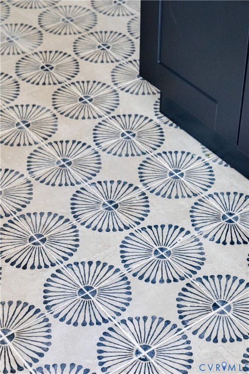 Patterned tile flooring featuring a radial design in a neutral and blue palette, complemented by a dark wood-finish cabinet base