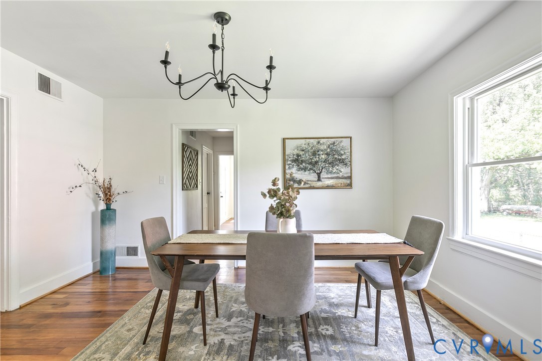 Dining area featuring wood-finish flooring, white walls, and a multi-light black chandelier