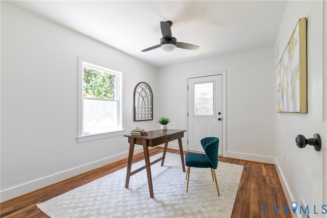 Bright room featuring wood-finish flooring, white walls, a ceiling fan with integrated lighting, and a window providing natural illumination