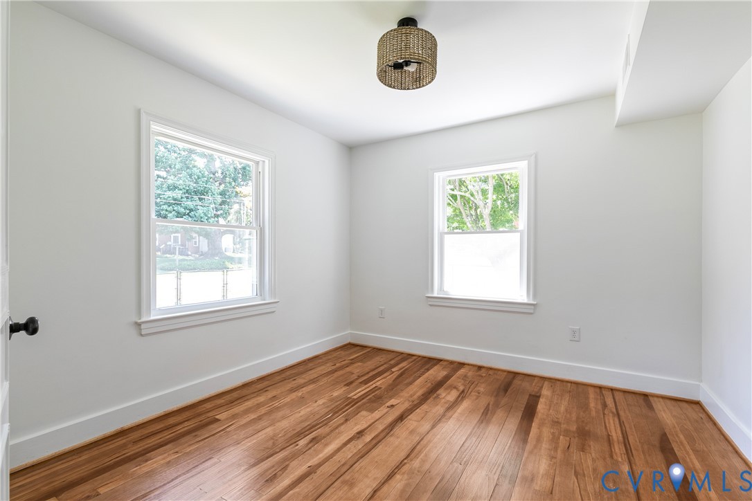Room featuring wood-finish flooring, two large windows, white walls, and a contemporary ceiling light fixture