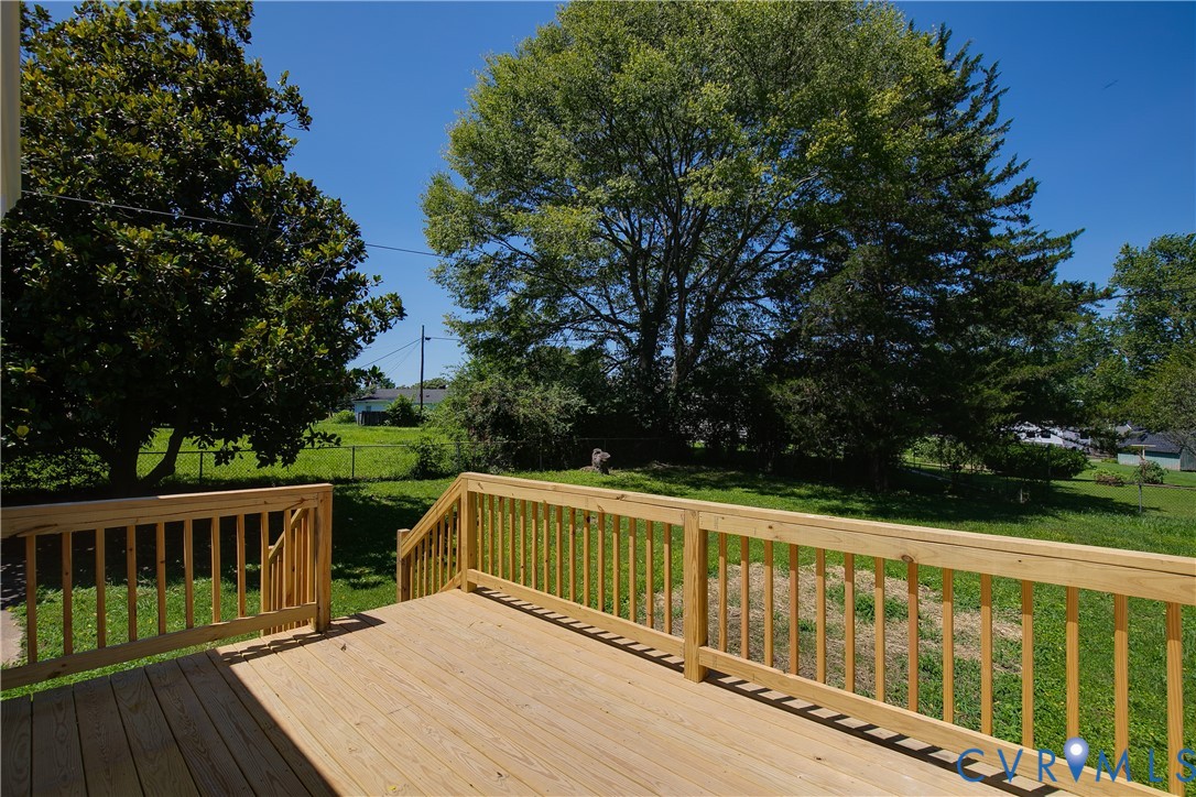 Spacious wooden deck with natural wood finish, featuring a railing system and steps