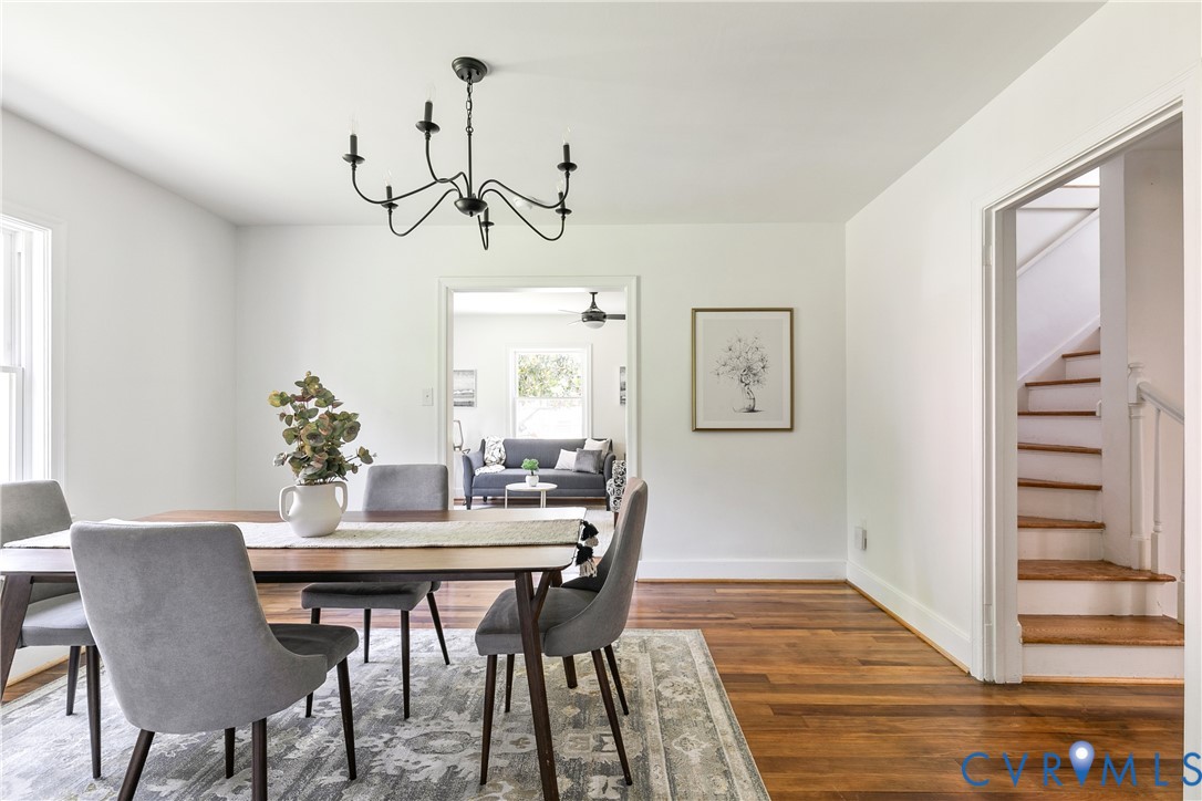 Dining area featuring wood-finish flooring, a contemporary chandelier, white baseboards, and a doorway opening to an additional living space