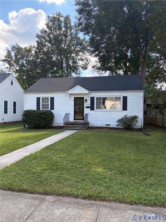 White exterior siding, black window shutters, gabled roofline, front entryway with a decorative hood, and concrete walkway