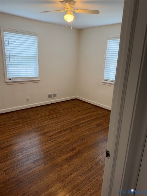 Room featuring wood-finish flooring, two windows with horizontal blinds, and a white ceiling fan with integrated lighting