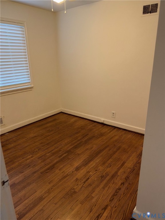Interior room featuring wood-finish flooring, neutral wall tones, and a window with horizontal blinds