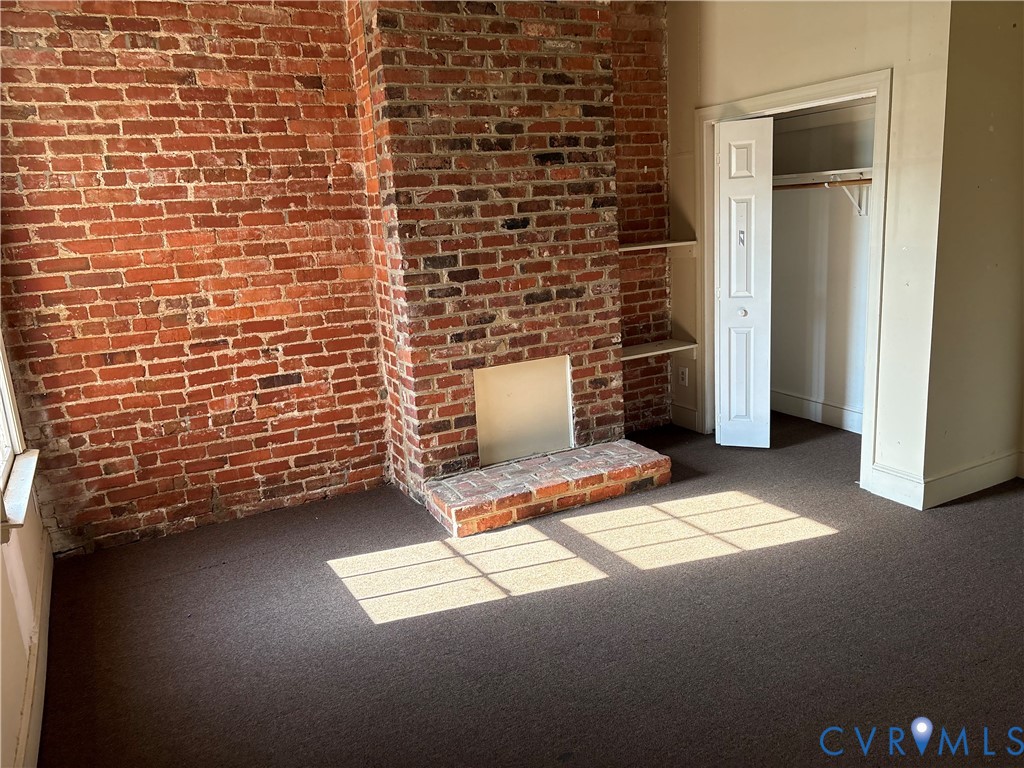 1st floor 5th bdrm or living rm. Exposed brick wall, built-in wall shelving, and recessed closet with louvered doors