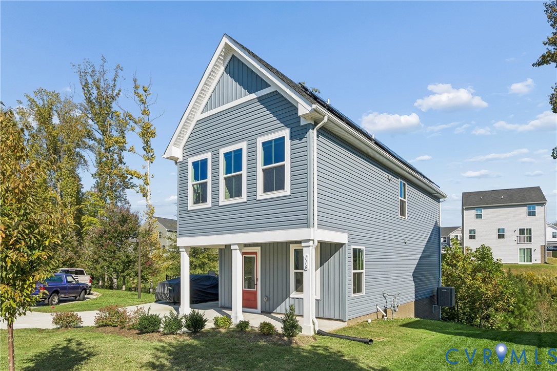 Two-story home with blue horizontal and vertical siding, a covered front porch with square columns, and solar panels installed on the roof