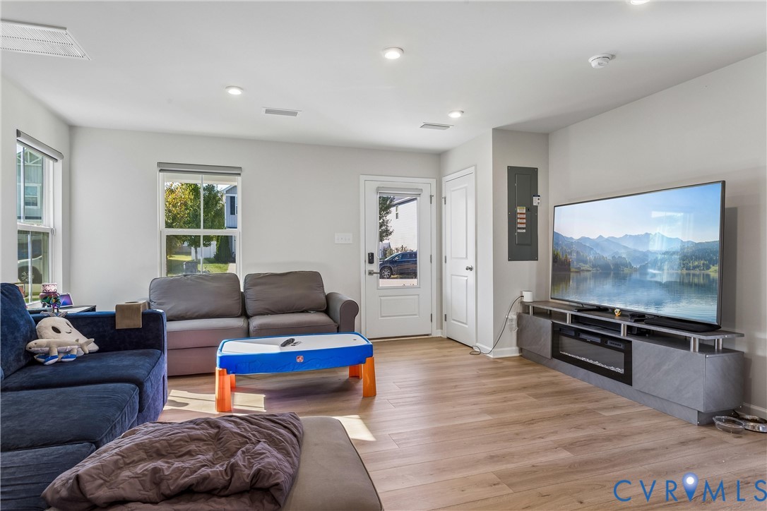 Open-concept interior featuring recessed lighting, wood-finish flooring, dual-pane windows, and a glass-paneled exterior door