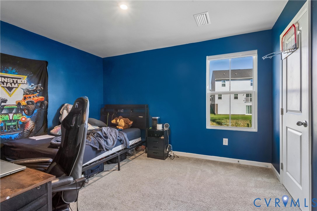Bedroom featuring neutral-toned carpeting, a single-hung window, and a paneled interior door