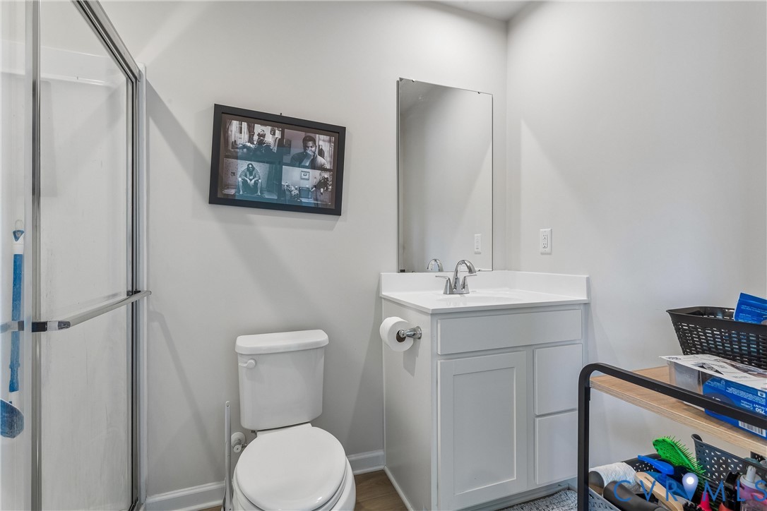 Bathroom featuring a glass-enclosed shower, white vanity cabinet with a stone countertop, integrated sink, and a wall-mounted rectangular mirror