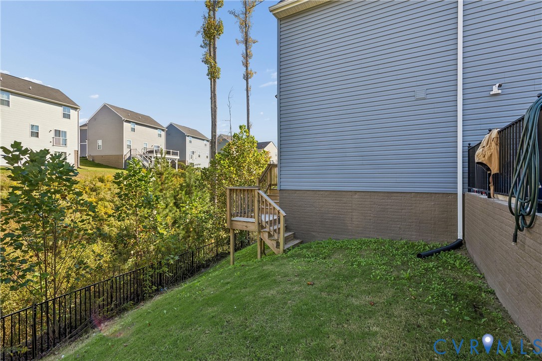 Exterior featuring blue horizontal siding, masonry foundation, wooden stairs, and a black metal fence