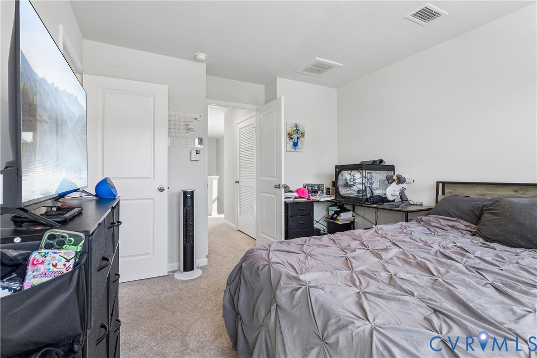 Neutral-toned interior space featuring light-colored wall-to-wall carpeting, white paneled interior doors, and crisp white wall paint