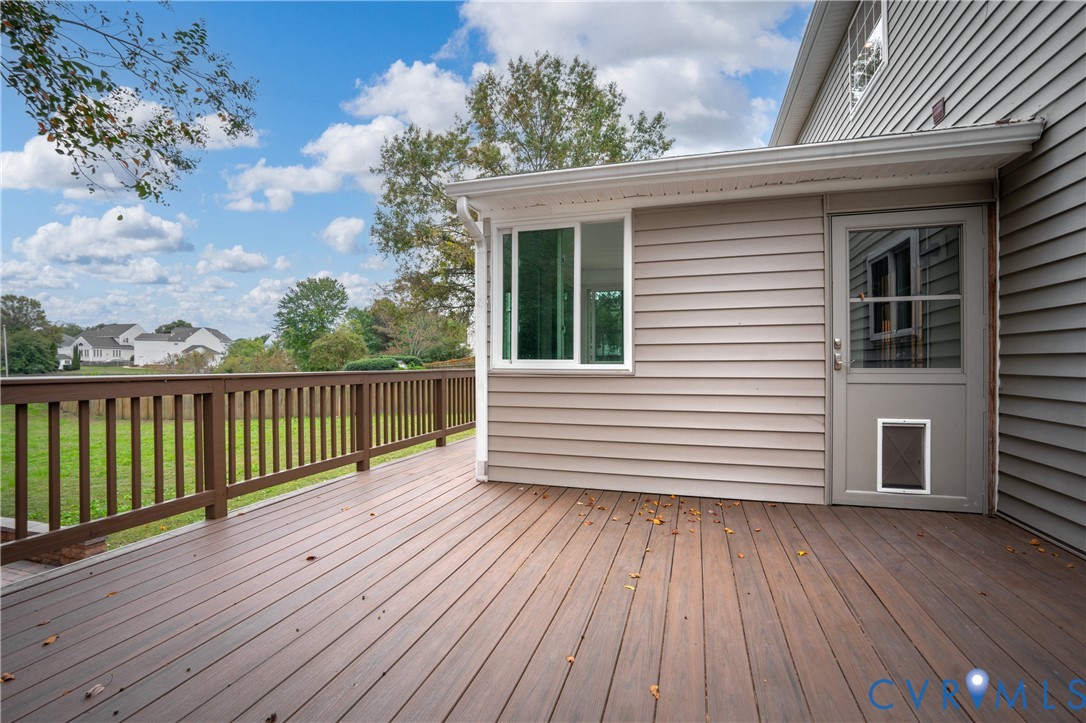 Elevated wood-finish deck with a rail balustrade, horizontal siding exterior, and a glass-paneled entry door