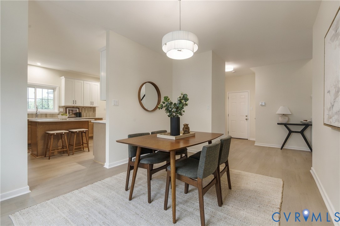 Dining area featuring wood-finish flooring, a contemporary multi-tiered pendant light, and neutral wall tones Dining area featuring wood-finish flooring, a contemporary multi-tiered pendant light, and neutral wall tones