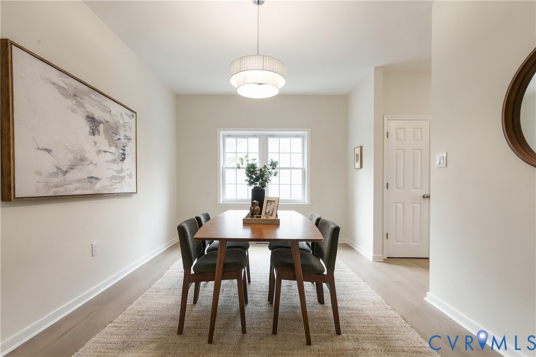Neutral interior featuring light-toned wood-finish flooring, multi-tier drum pendant lighting, and a multi-pane grid window Neutral interior featuring light-toned wood-finish flooring, multi-tier drum pendant lighting, and a multi-pane grid window